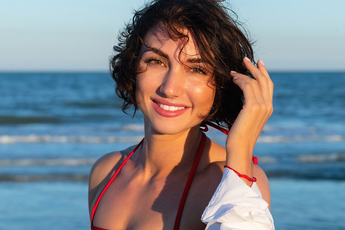 Schöne junge sexy Frau mit fit trainiertem, schlankem Körper und rotem Badebekleidungs-Bikini posiert an einem Sandstrand fotografiert von Mazelle Photography Fotostudio®