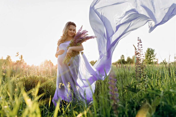 Schwangere Frau auf der Wiese beim Blumen pflücken - Babybauchfotografie mit dem Mazelle Photography Fotostudio® - Schwangerschaftsfotografie - Schwangere Frau in der Natur