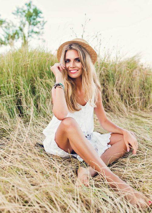 Porträtfotografie eines blondes Mädchen in voller Länge mit langen Haaren posiert auf trockenem Gras auf der Insel Rügen. Das Mazelle Photography Fotostudio® macht das Fotoshooting der Portraitfotografie an der Ostsee in der Natur in Mecklenburg-Vorpommern.